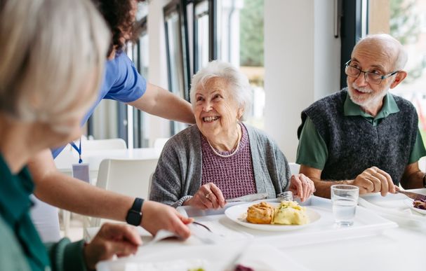 Caregiver Serving Lunch to Elderly Residents in a Care Home
