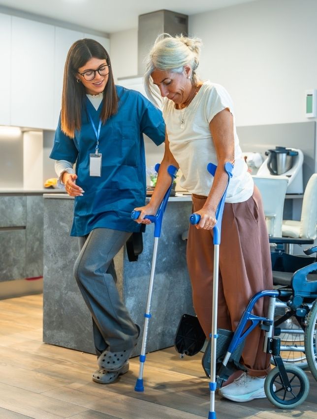 Caregiver assisting elderly woman during physical at home